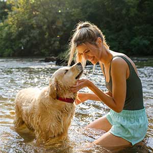 A woman and dog playing in a stream