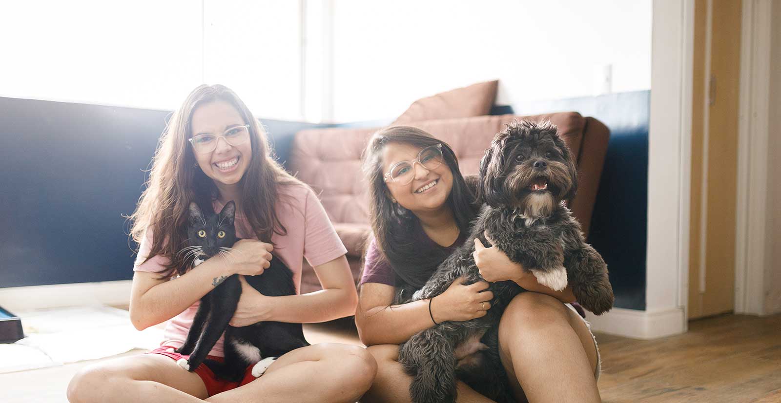 Two women with their dog and cat